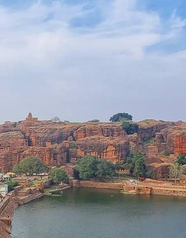 Large rock formation by a lake with a small town below.