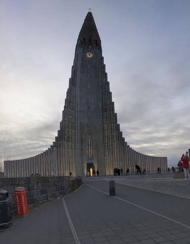 A tall, modern church with people around it.