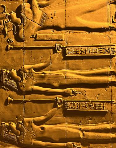 Illuminated ancient Egyptian carvings on a wall.