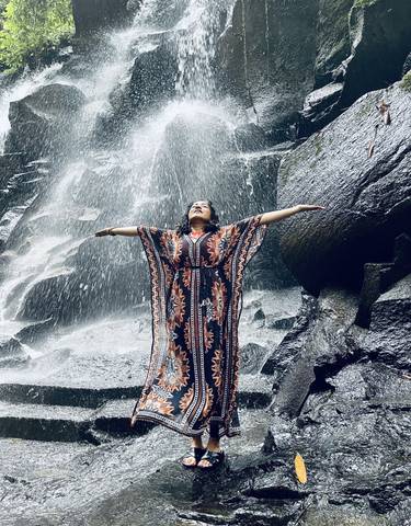 Person posing near a waterfall in a flowing dress.