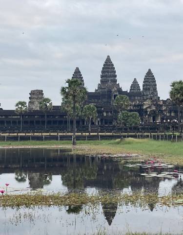 Ancient temple complex with water and palm trees in the foreground.