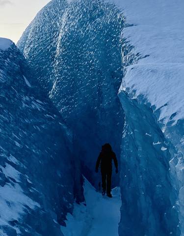 A person walking through an icy crevasse in a glacier.