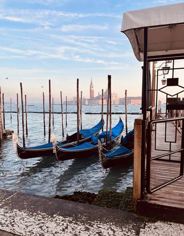 Row of gondolas docked with a historic tower in the background.