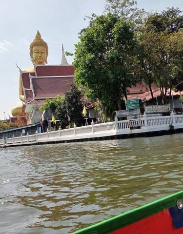 Golden Buddha statue next to a waterway.