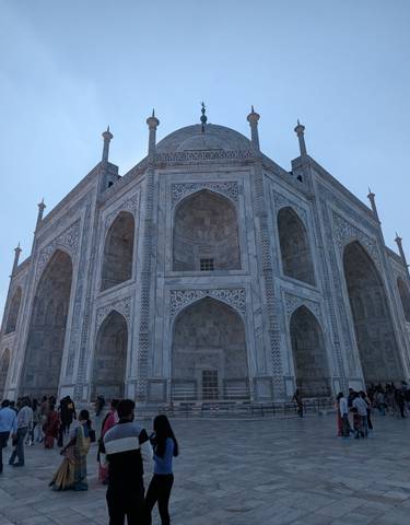 The Taj Mahal with many visitors around, seen on a bright day.