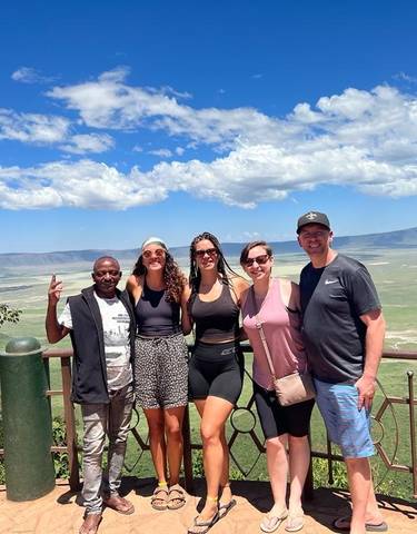 Group of people posing with a scenic landscape in the background.