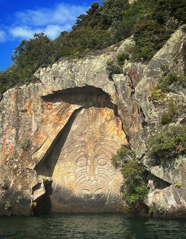 A large rock carving depicting an intricate face design.