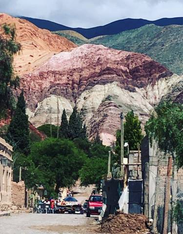 Colorful layered mountains with greenery at the base, likely in Purmamarca.