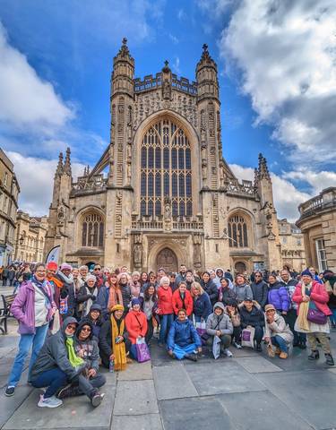 Large group posing in front of a historic cathedral.