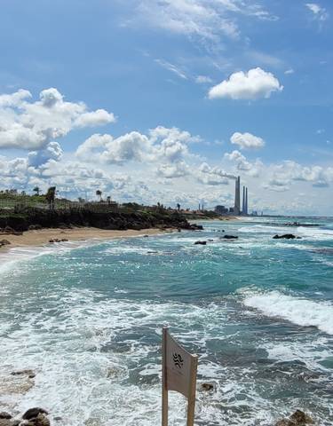 Coastline with rocky beach and distant city skyline.