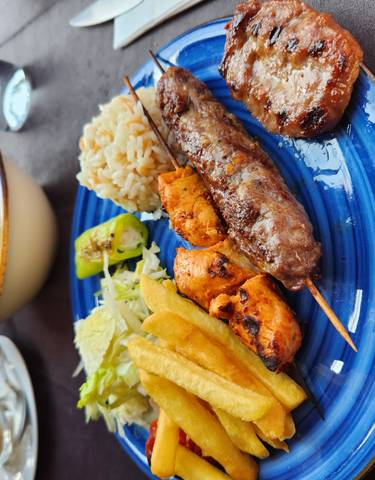Assortment of grilled meats and vegetables on a blue plate.