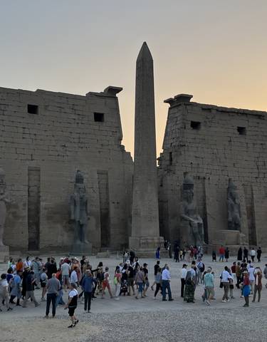 Large ancient temple entrance with an obelisk and many tourists.