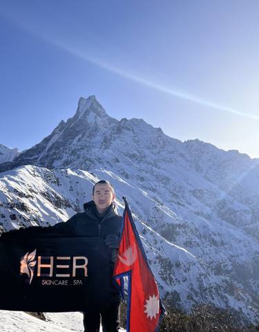Person standing with a flag against a backdrop of a mountain resembling a fishtail.