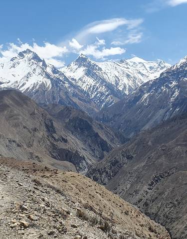 Vast mountainous landscape with snowy peaks under a clear sky.