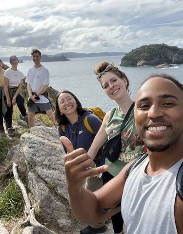 A group of people posing on a cliff with a scenic ocean view.