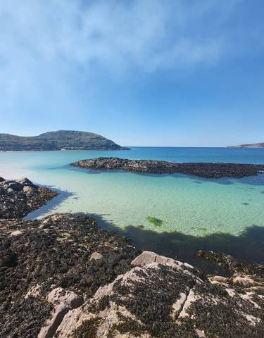Panoramic view of a pristine beach with clear blue water and rocks