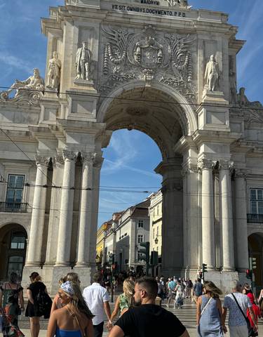 Arch at famous Portuguese square bustling with people.