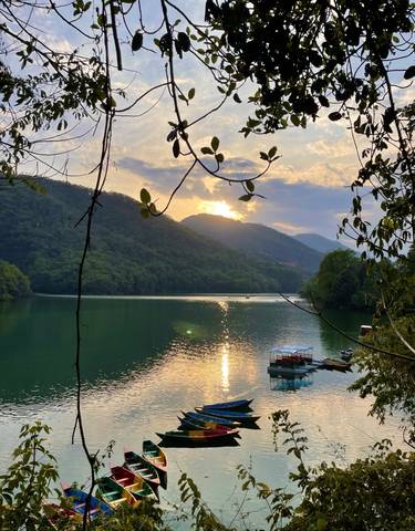 A calm lake at sunset with mountains in the background.