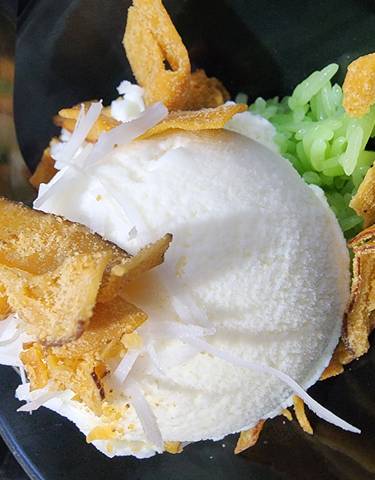 Dessert with coconut ice cream and toppings in a bowl.