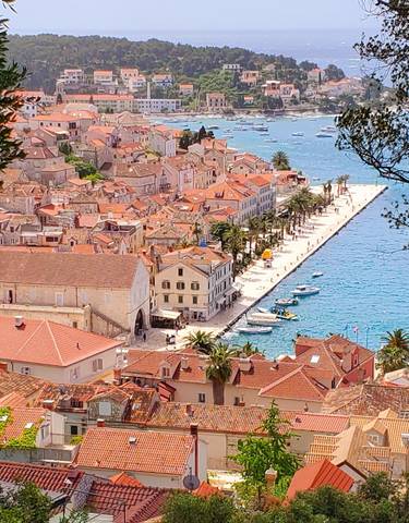 Aerial view of a coastal town with red roofs and clear blue waters.