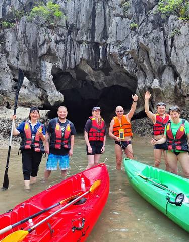 Group of people kayaking in front of a cave.
