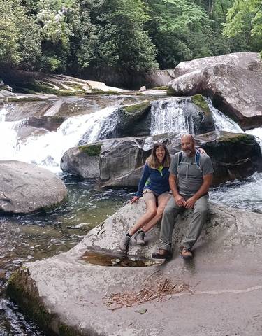 Two people sitting on a rock by a waterfall.