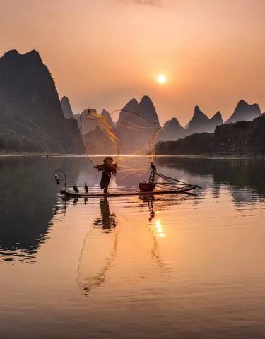 A fisherman casting a net at sunset in Yangshuo.