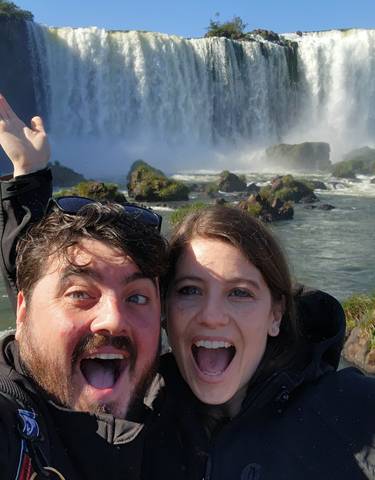 Couple excitedly posing in front of Iguazu Falls.