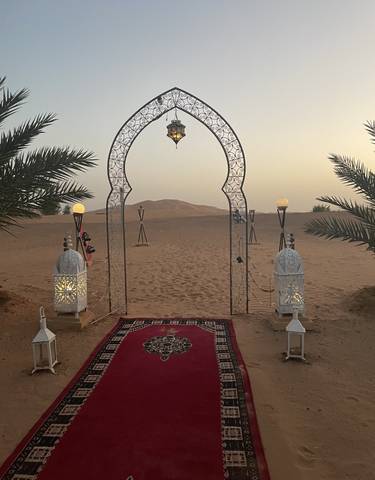 Decorative gate in a desert with lanterns.