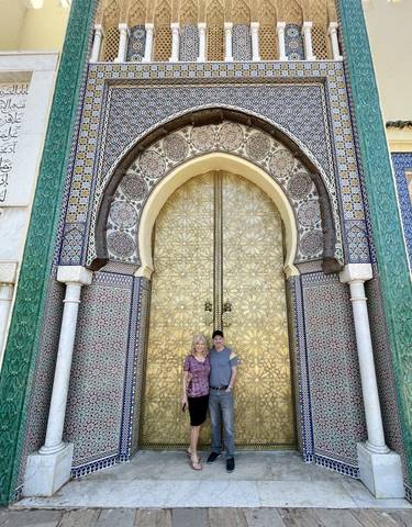 Two people standing in front of a large decorative gate