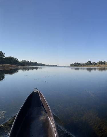 Canoe on a calm river with trees on the banks