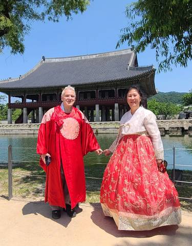 Couple wearing traditional Korean hanbok in front of a historic palace.