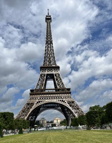 The Eiffel Tower in Paris against a cloudy blue sky.