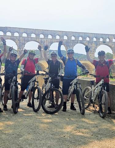 Cyclists posing in front of the Pont du Gard aqueduct.