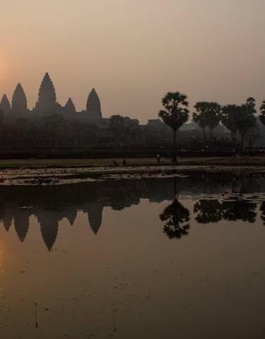 Angkor Wat silhouette at sunrise with reflections.