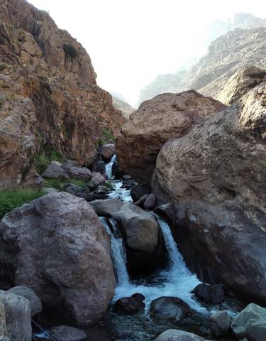 Flowing stream through rocky terrain with mountains in the background.