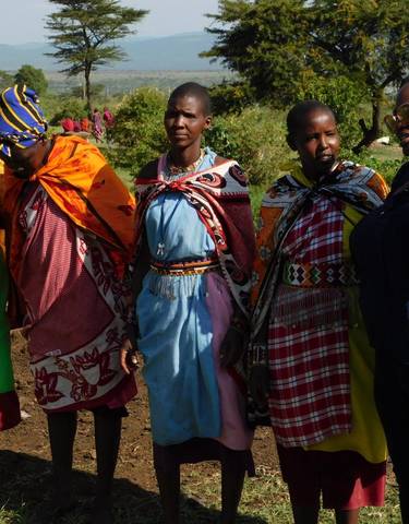 Women in traditional Maasai attire standing outdoors.