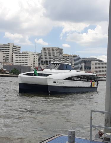 Boat cruising on a river with city buildings in the background.