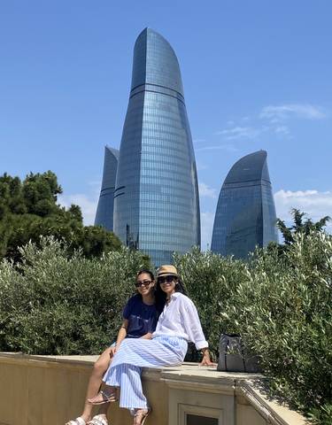 Two women posing with modern skyscraper in the background.
