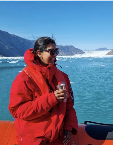 Person in red jacket standing with a glacier in the background.