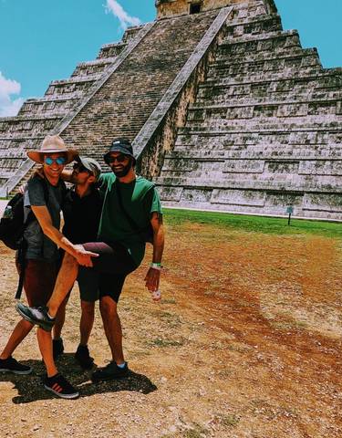 Two people playfully posing in front of an ancient pyramid.