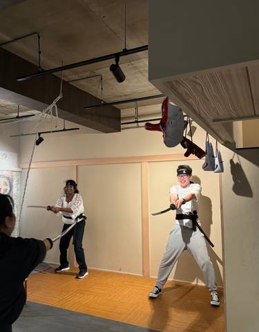 Two people practicing martial arts with swords indoors.