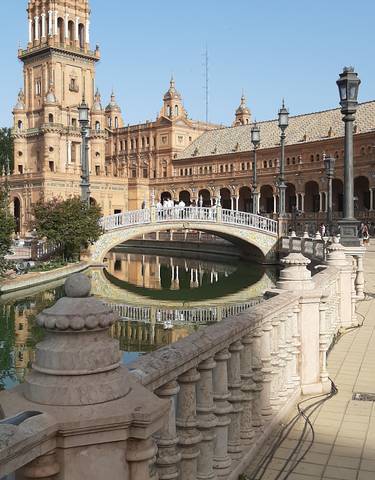 Ornate architecture and bridge with reflections on water.