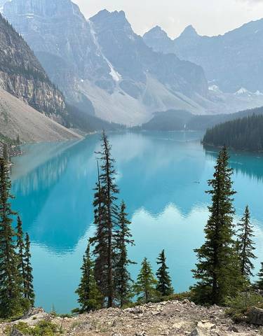 Bright blue lake surrounded by forested mountains.