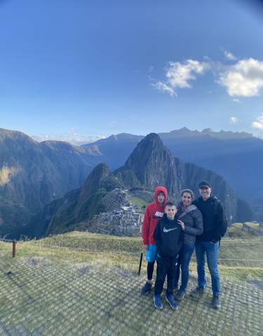 Family posing with the Machu Picchu ruins and mountains in the background.