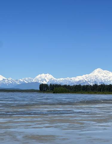 Snow-capped mountains with a river or lake in the foreground.