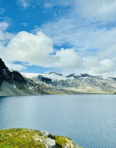 Panoramic view of a tranquil lake surrounded by snow-capped mountains.