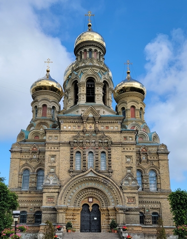 An ornate church with golden domes under a clear sky.