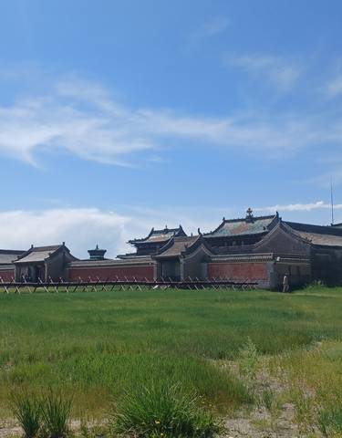 Historical architecture in a grassy plain under a blue sky.