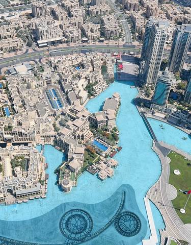 Aerial view of a cityscape with modern skyscrapers and a large water feature.